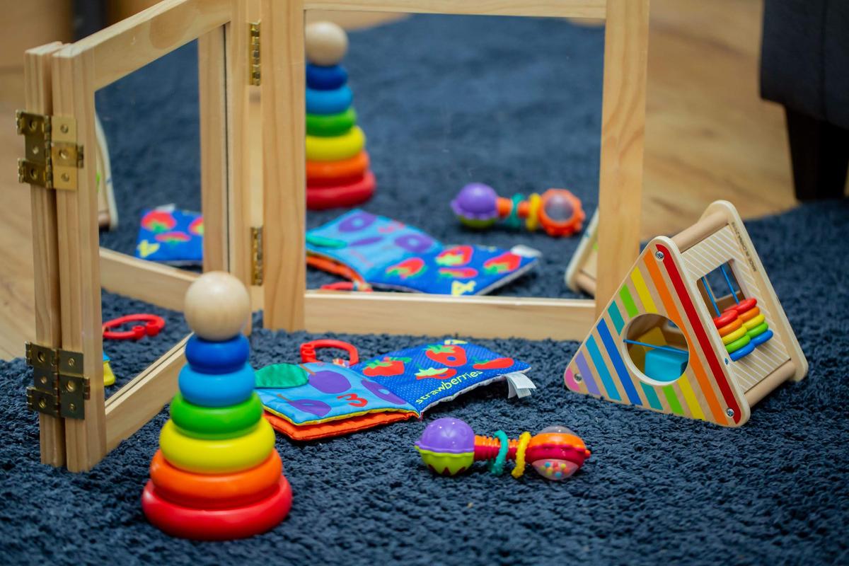 A carer holding a baby in a bright, clean nursery room