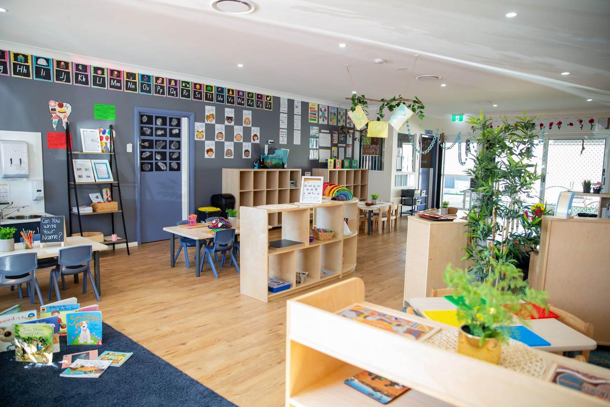 A diverse group of happy children in a preschool classroom learning with a teacher